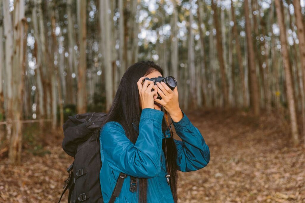A woman takes a picture in the woods