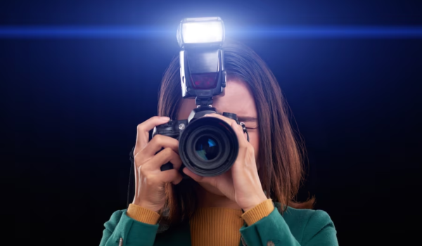 Woman holding a camera with flash covering her face