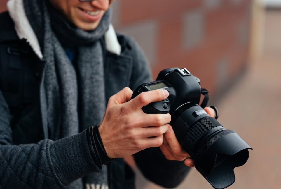 man with scarf looks at photos in the camera