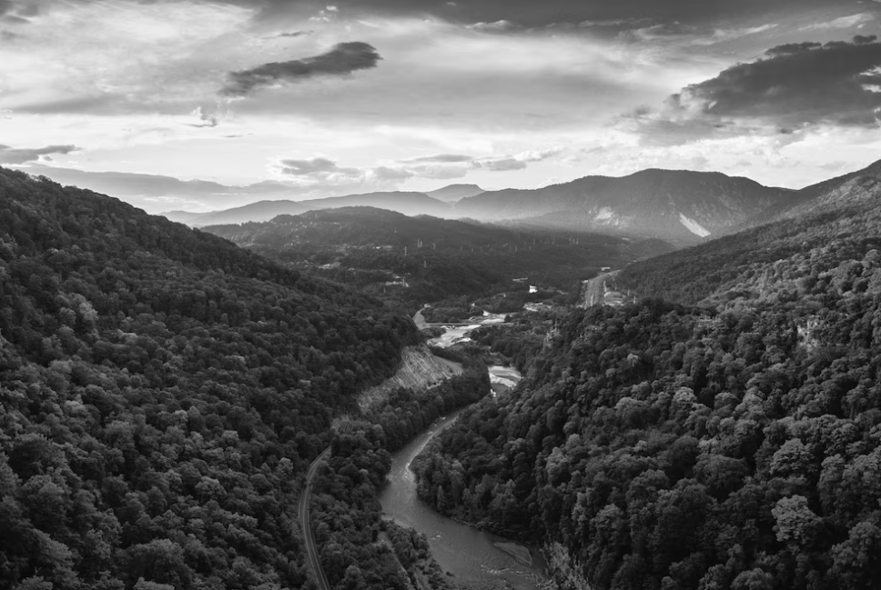 aerial greyscale shot of mountainous under the cloudy sky