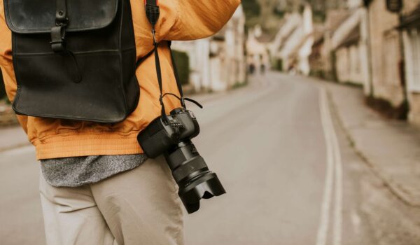 Camera with strap hanging on photographer’s shoulder