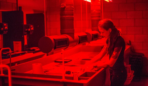 a woman working with prints in a darkroom